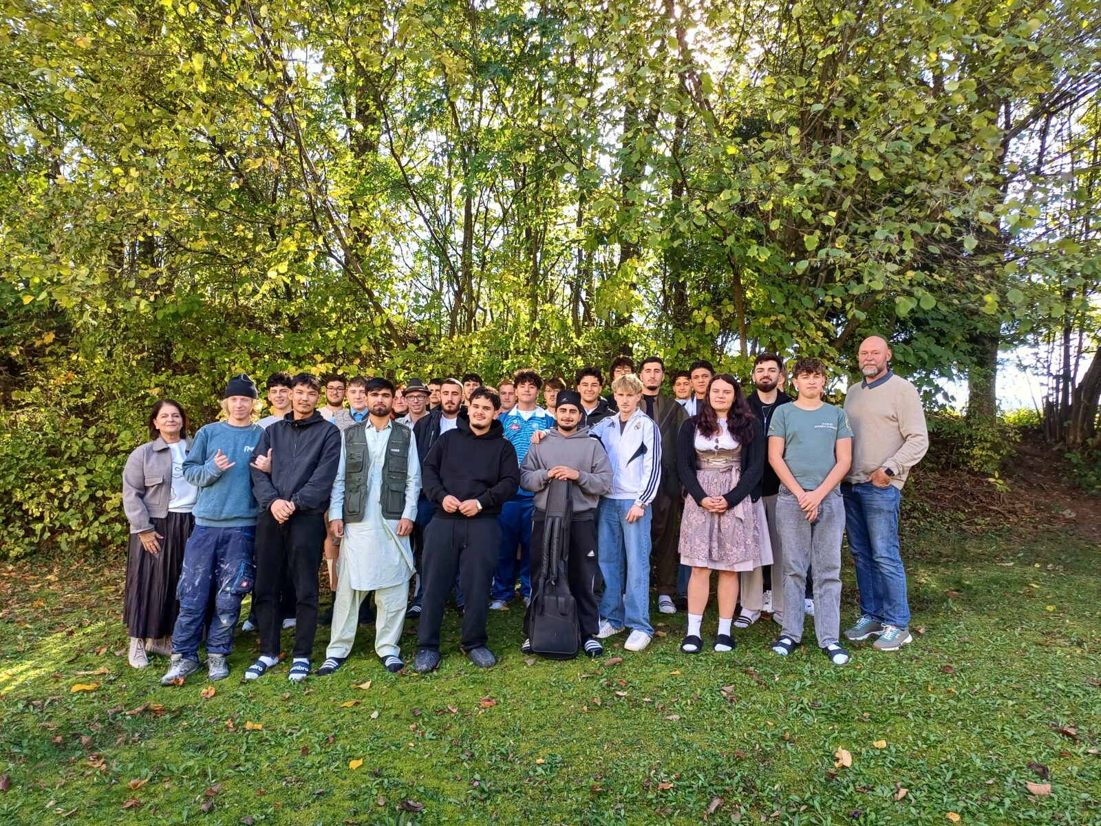 Schulleiter und Fachlehrerin mit Schülergruppe auf einer Wiese