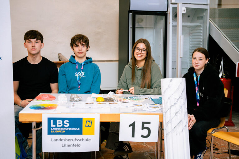 Landesberufsschule Lilienfeld: Vier Schülerinnen und Schüler präsentieren am Stand Nummer 15 Materialien und Farbmuster.